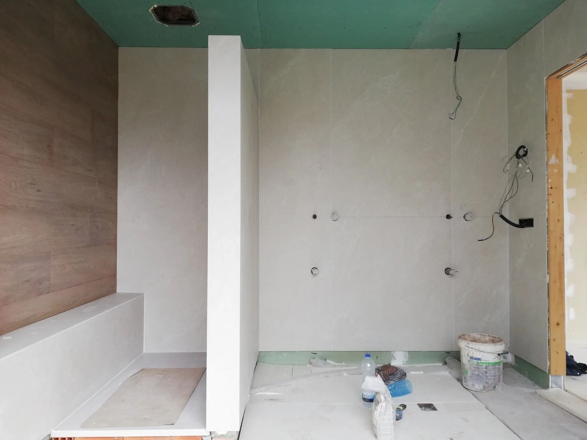 Un baño en construcción con techo verde y paredes blancas.