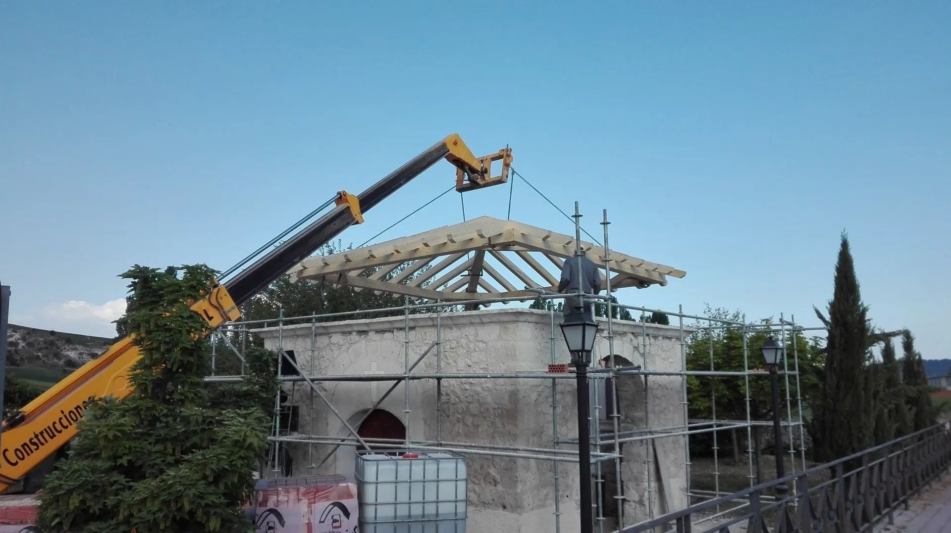 Una grúa está levantando una estructura de madera en la parte superior de un edificio.