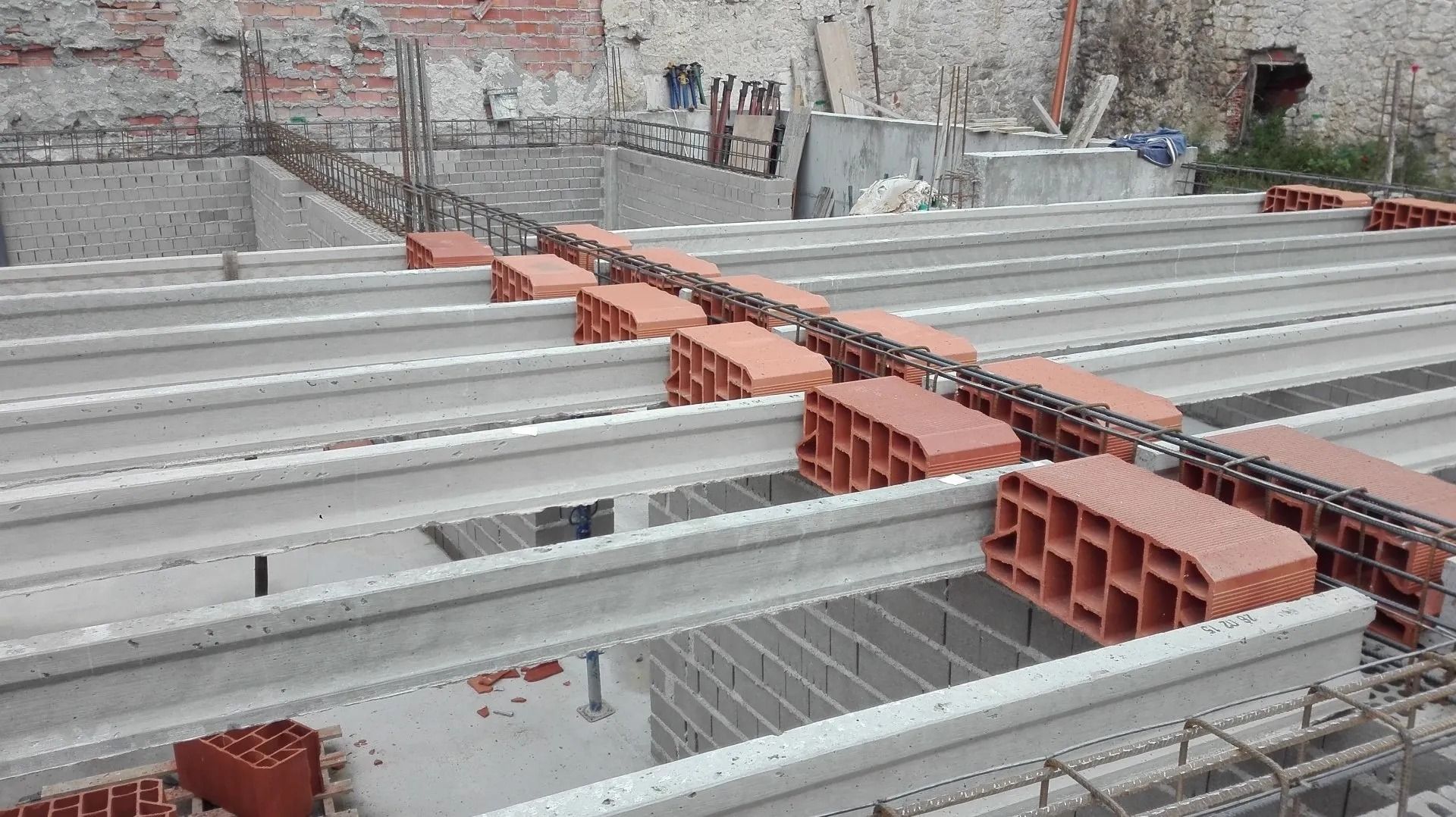 Una obra en construcción con muchos ladrillos y vigas de hormigón.