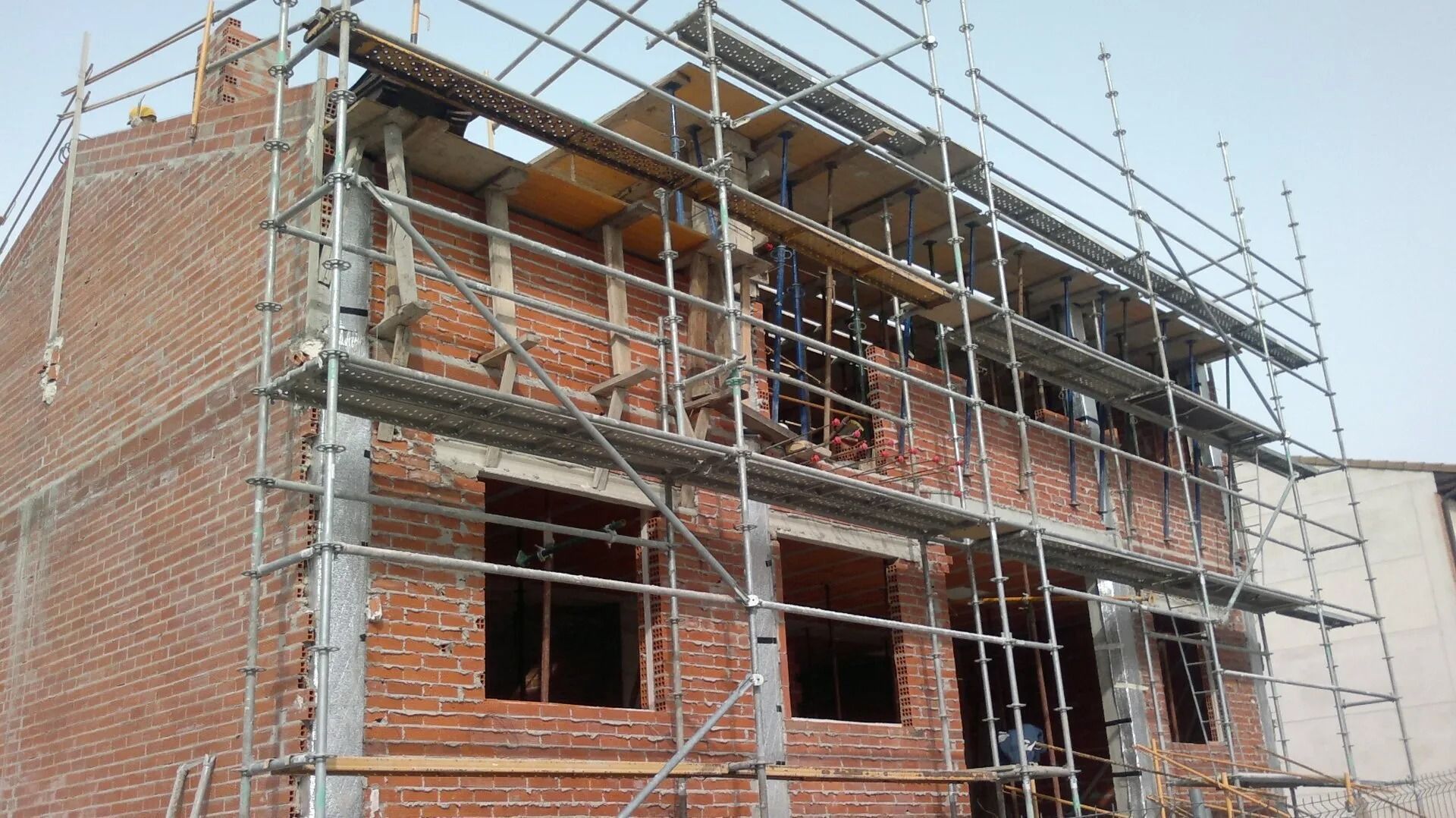 Se está construyendo un edificio de ladrillo con andamios alrededor.