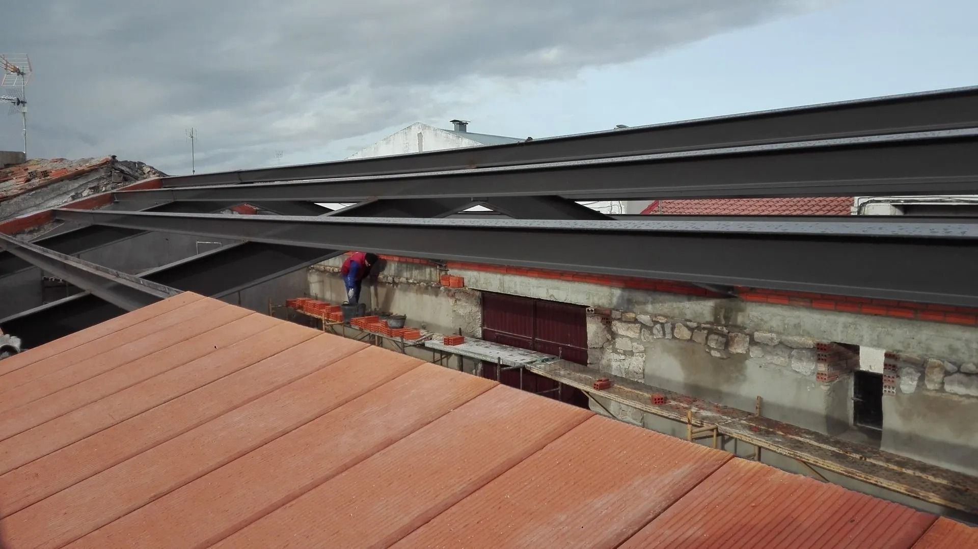 Un hombre está trabajando en el tejado de un edificio.