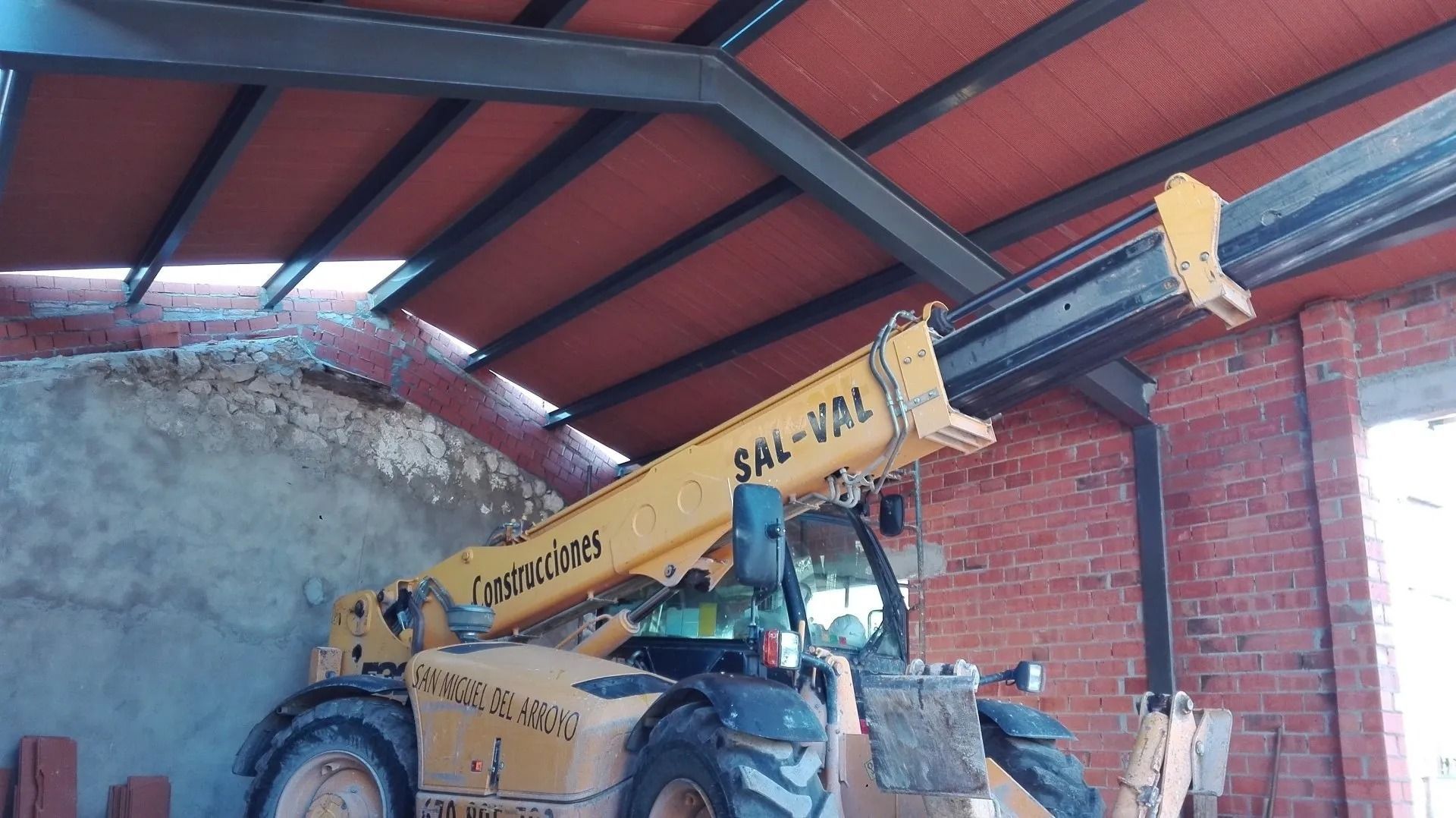 Un tractor amarillo está estacionado en un edificio de ladrillos.
