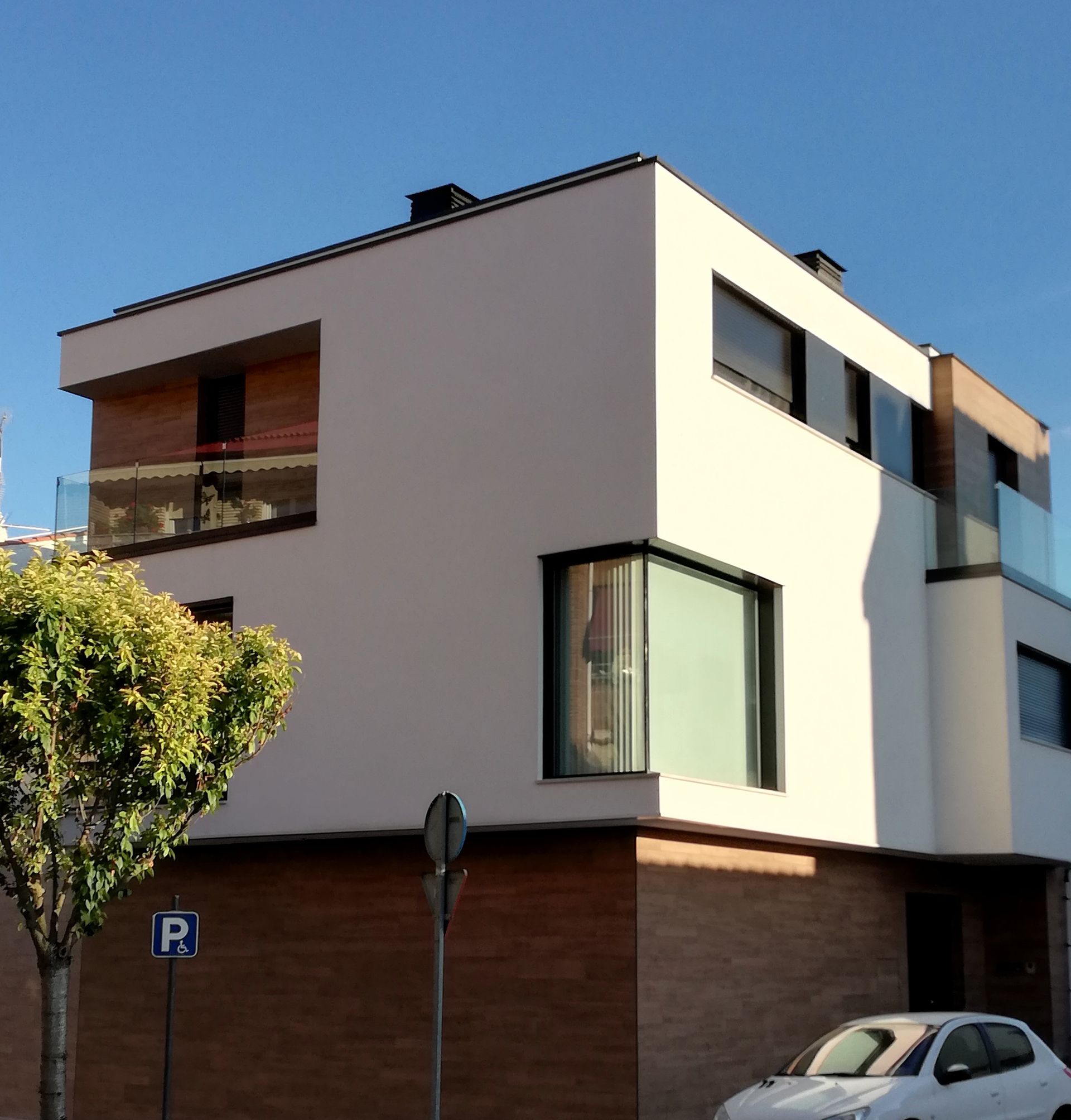 Un coche blanco está aparcado delante de un edificio con un cartel que dice r