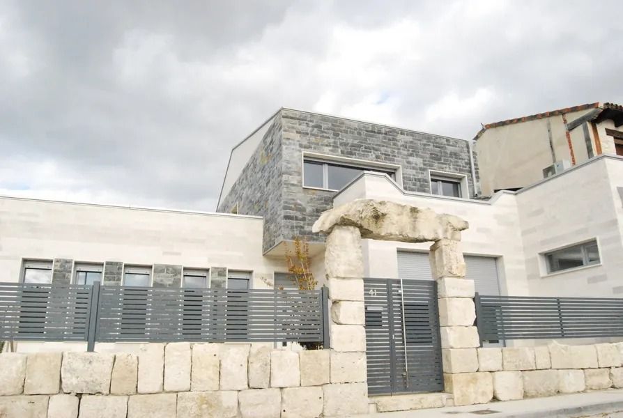 Una casa con una valla y una estatua delante de ella.