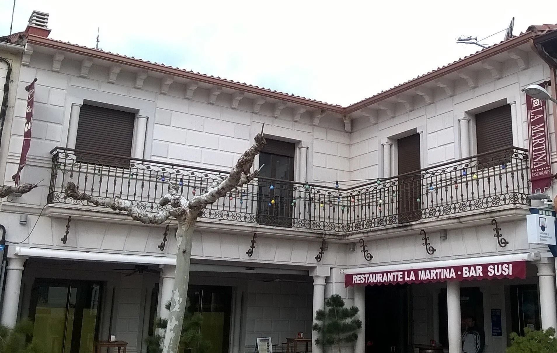 Un edificio blanco con un cartel rojo que dice restaurante la martina bar susi