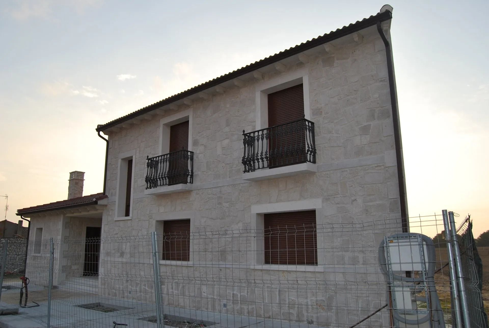 Una casa de piedra con balcones y una valla alrededor.