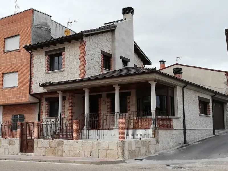 Una casa con un porche y un edificio de ladrillo al fondo.