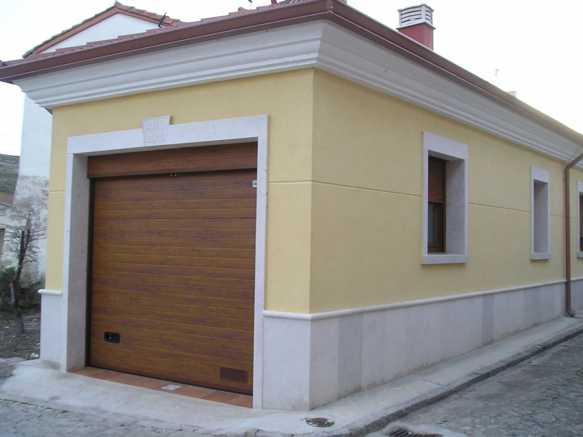 Un edificio amarillo con una puerta de garaje de madera