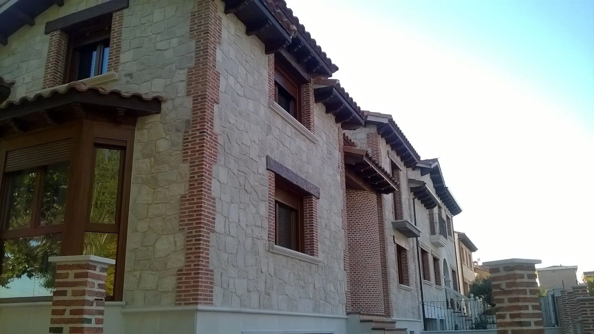 Un edificio de ladrillo con muchas ventanas y un cielo azul al fondo.