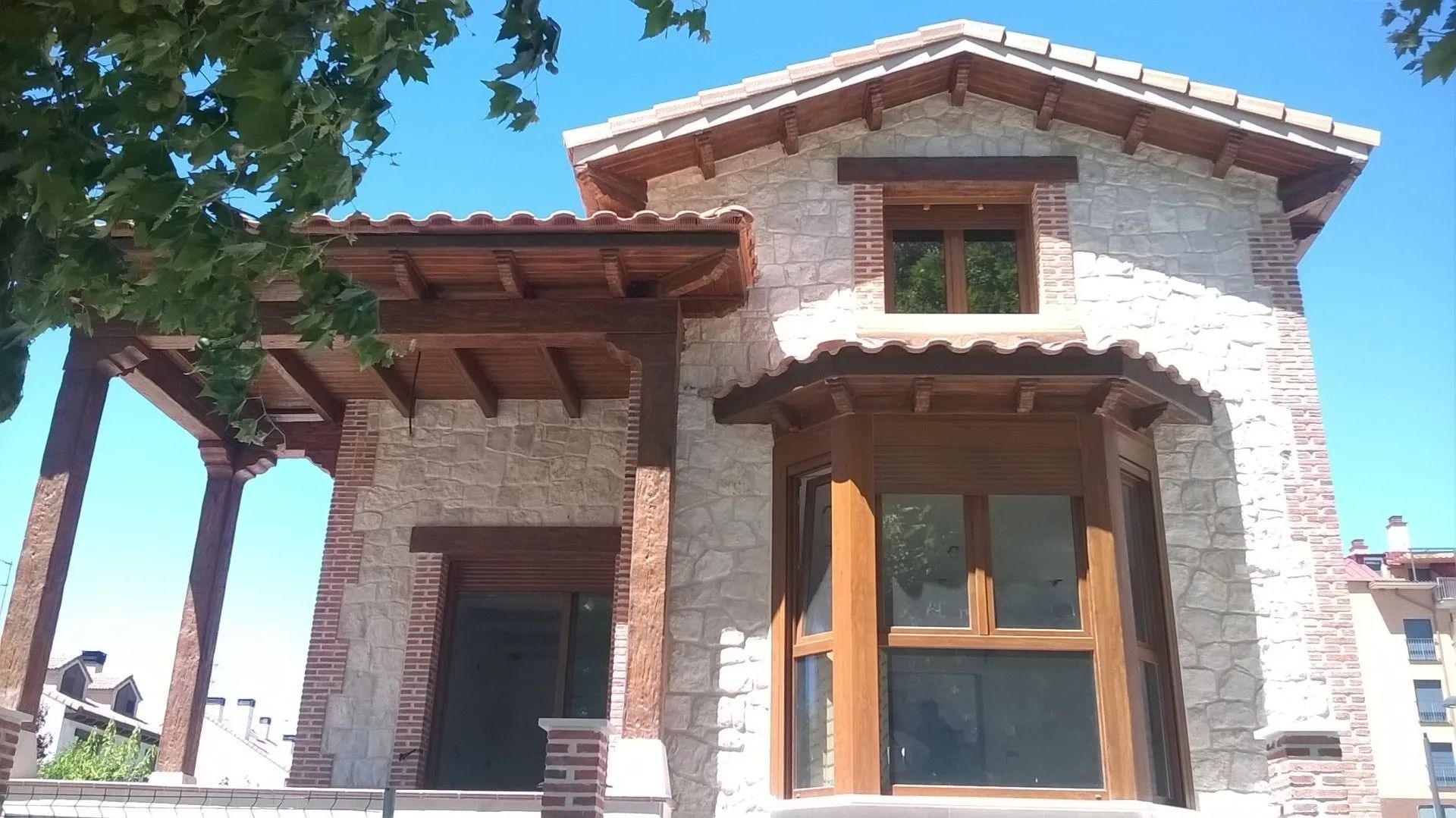 Una casa de piedra con un porche de madera y un cielo azul al fondo.