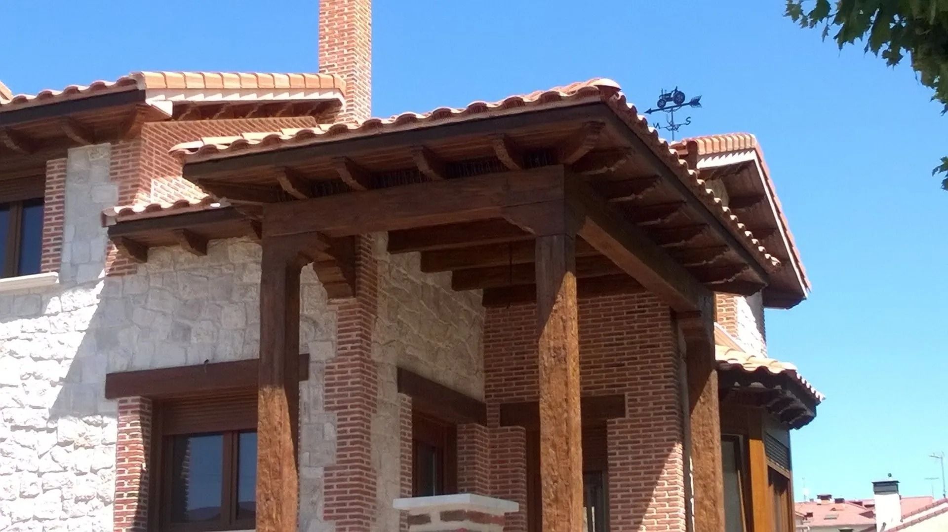 Una casa de ladrillo con un porche de madera y un techo de tejas