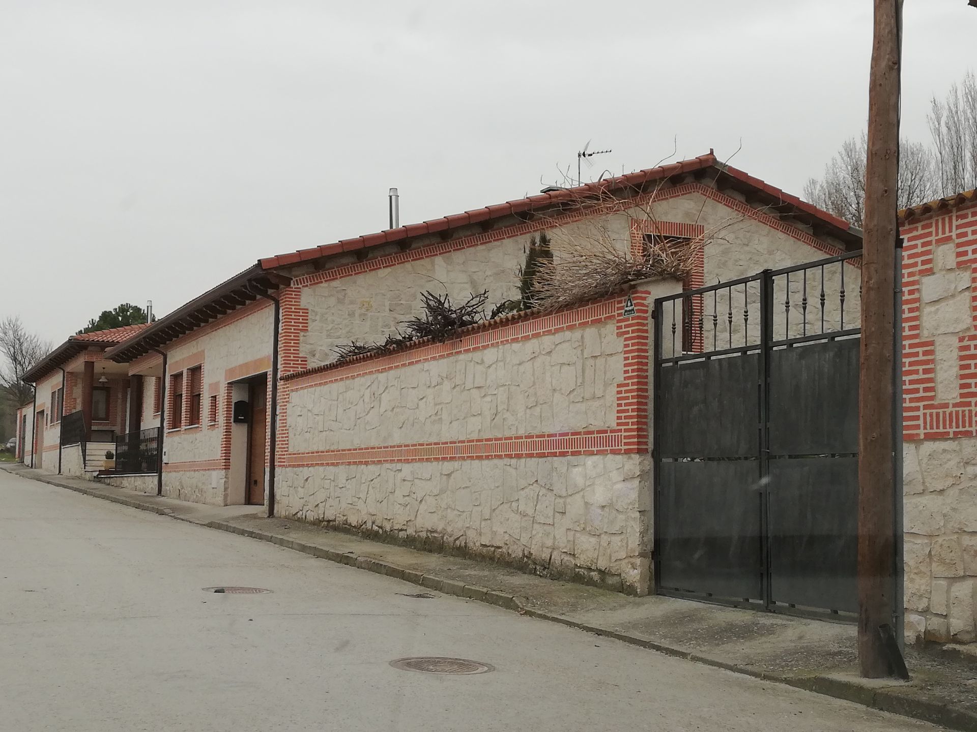 Una casa con techo rojo está sentada al costado de una carretera.