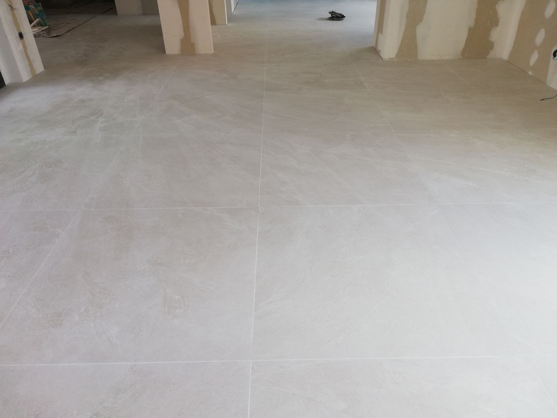 Un suelo de baldosas blancas en una habitación vacía con un zapato encima.