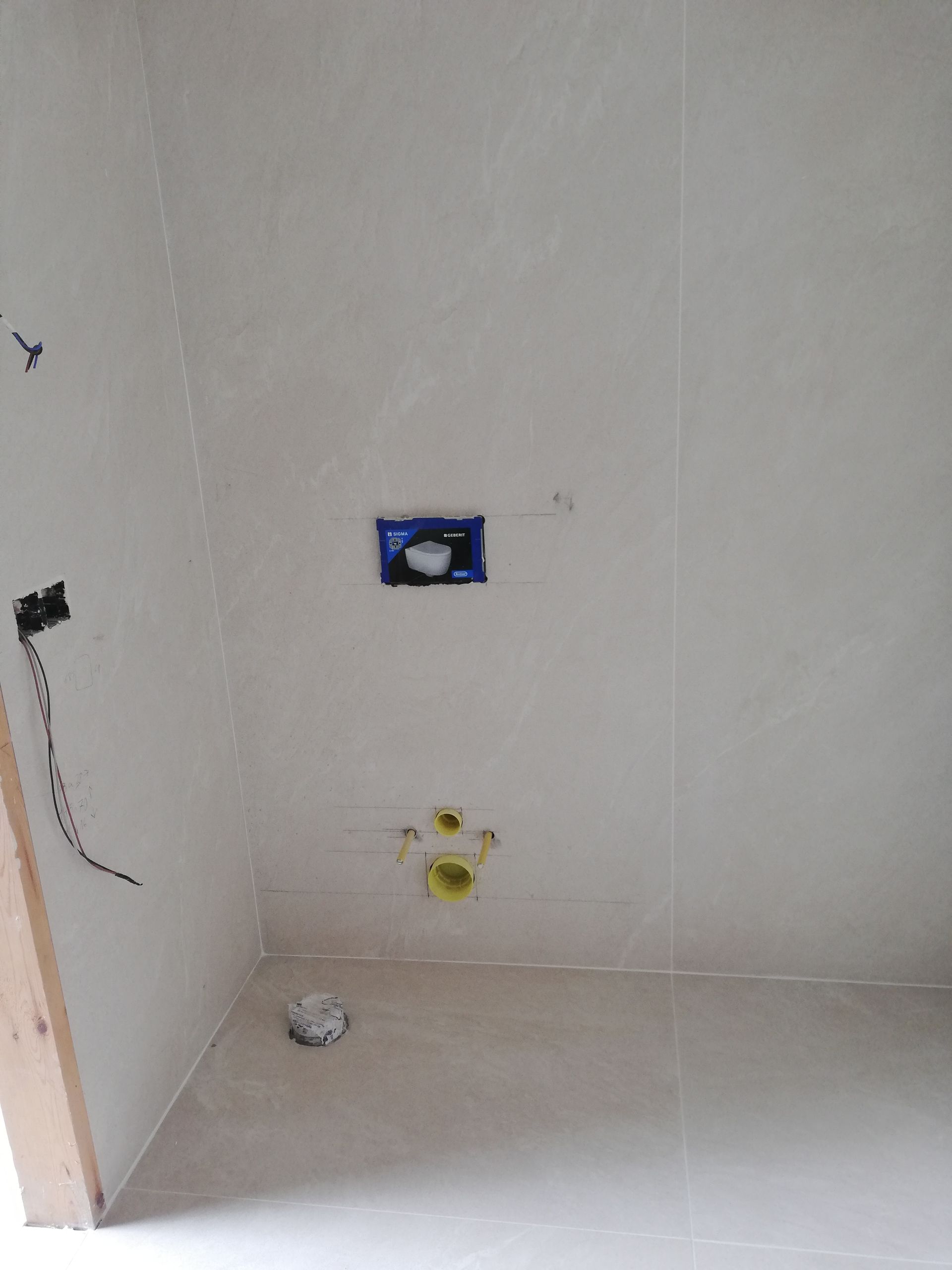 Un baño con un inodoro en la pared y un lavabo en el suelo.