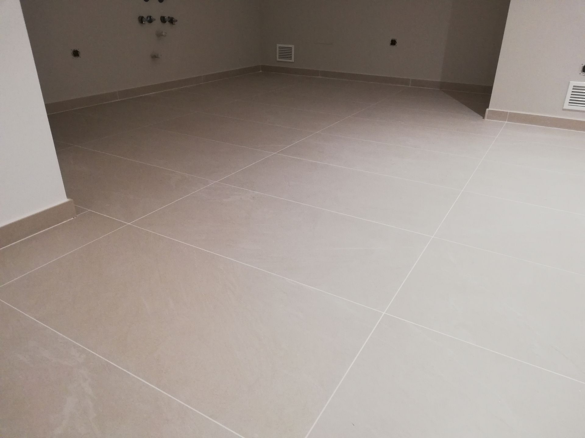 Una habitación con suelo de baldosas y una pared blanca.