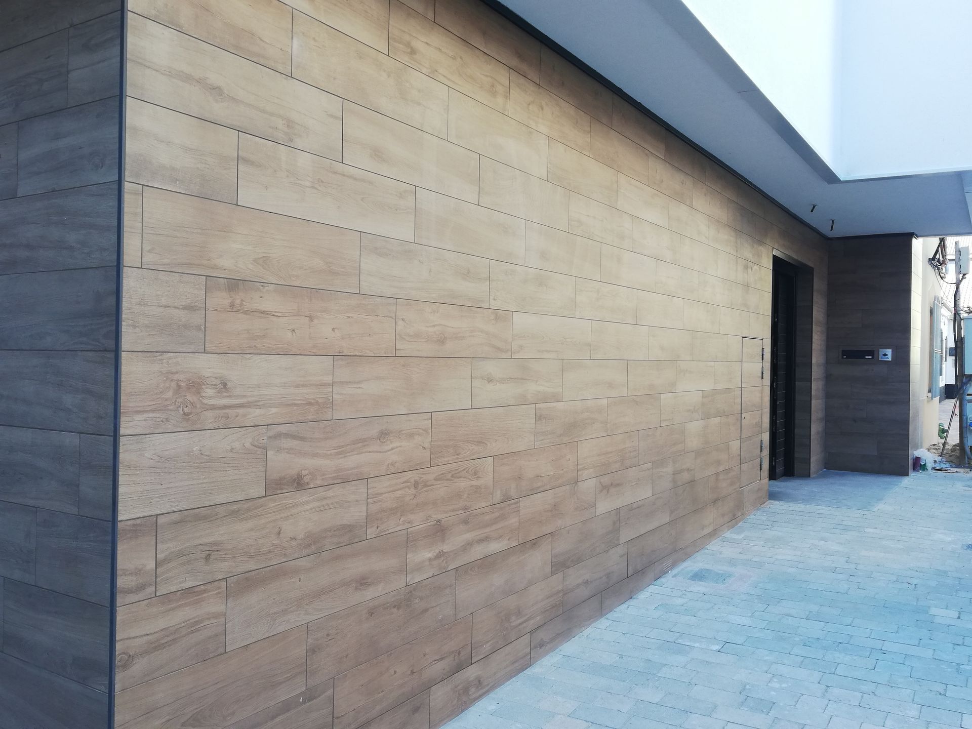 Una pared de ladrillos con una puerta al costado.