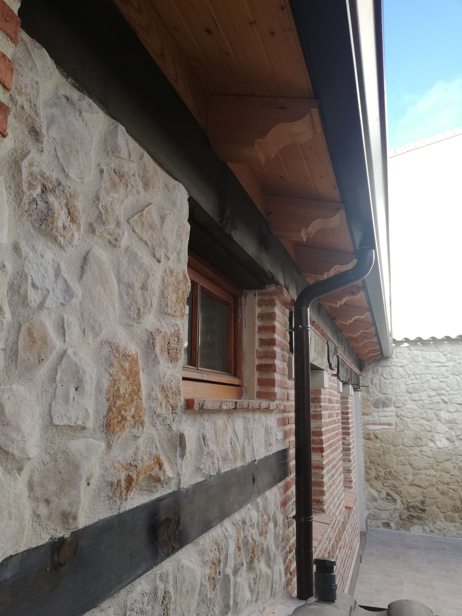 Un muro de piedra con una ventana y un techo de madera.