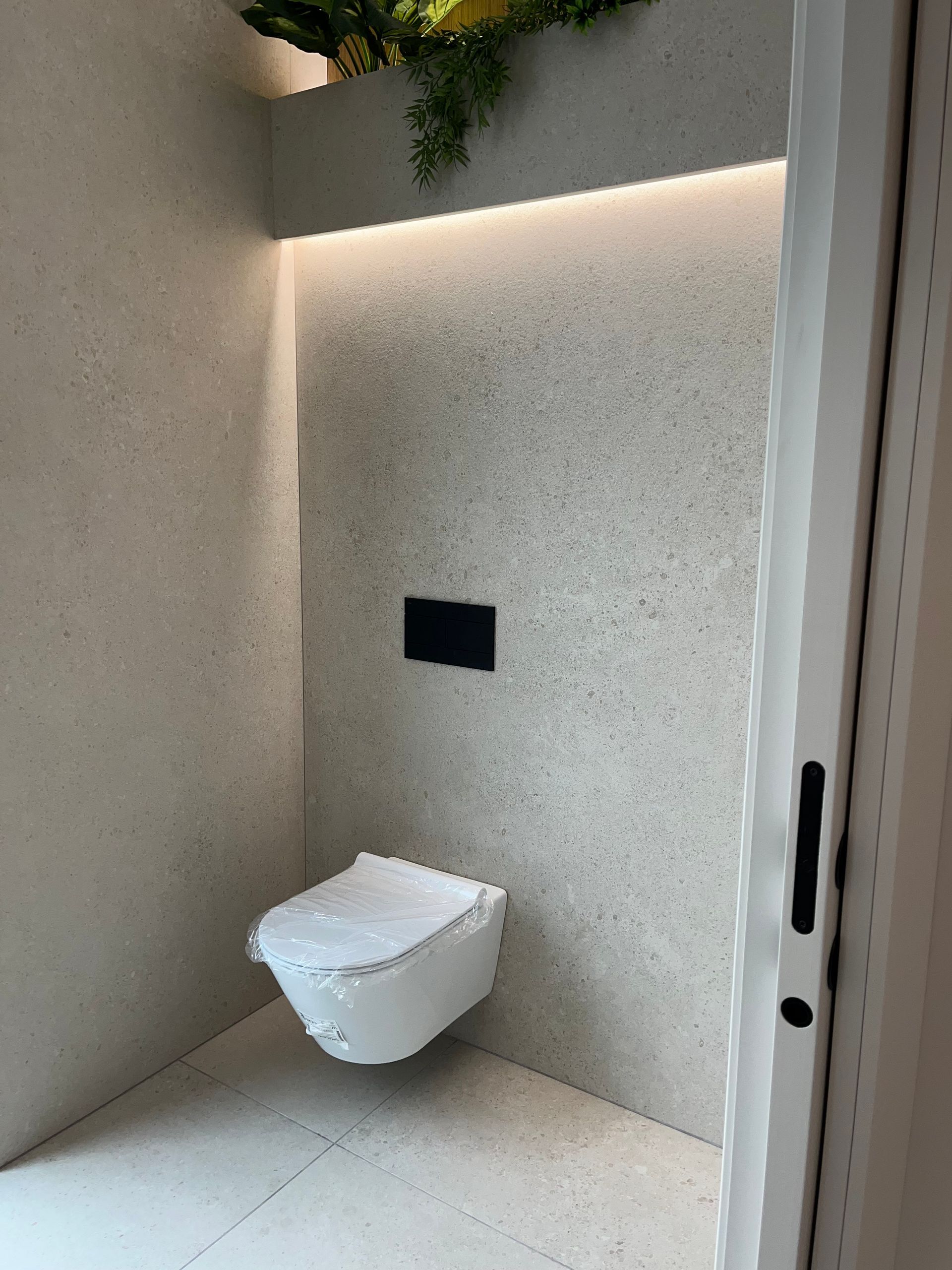 Un baño con un inodoro colgado de la pared.