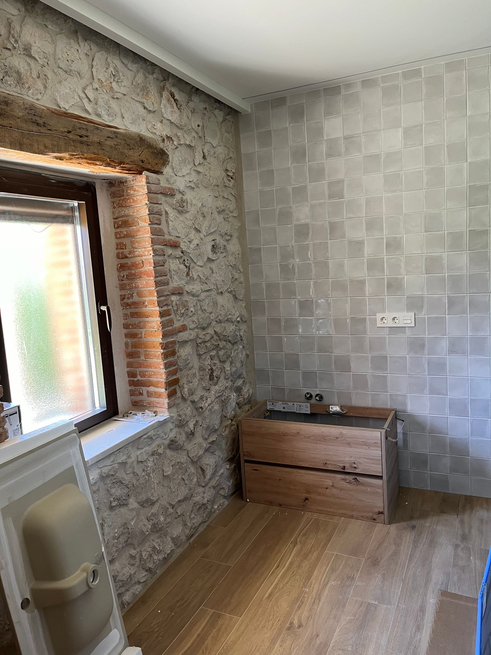 Una habitación con una pared de ladrillo, piso de madera y una ventana.