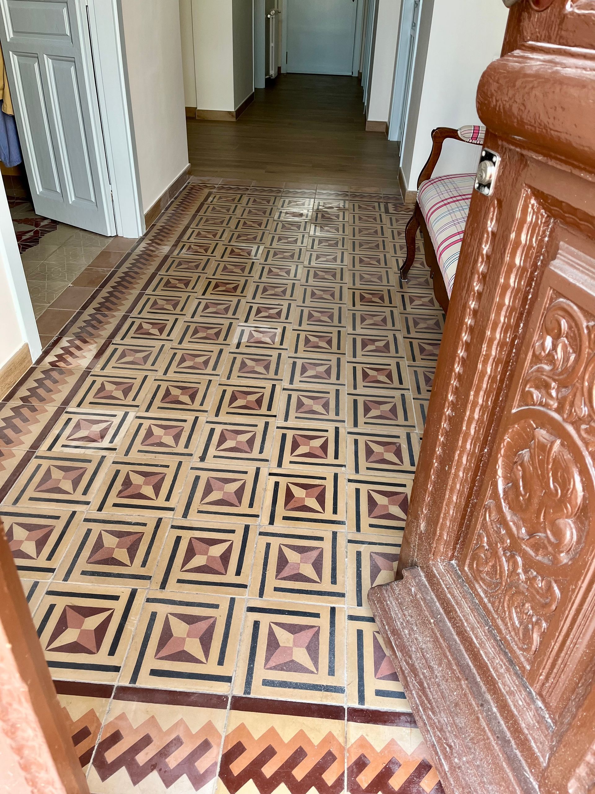 Un pasillo con suelo de baldosas y una puerta de madera.