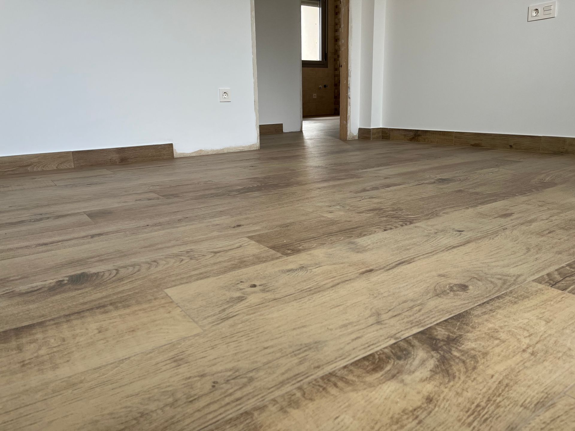 Una habitación con suelo de madera y paredes blancas.