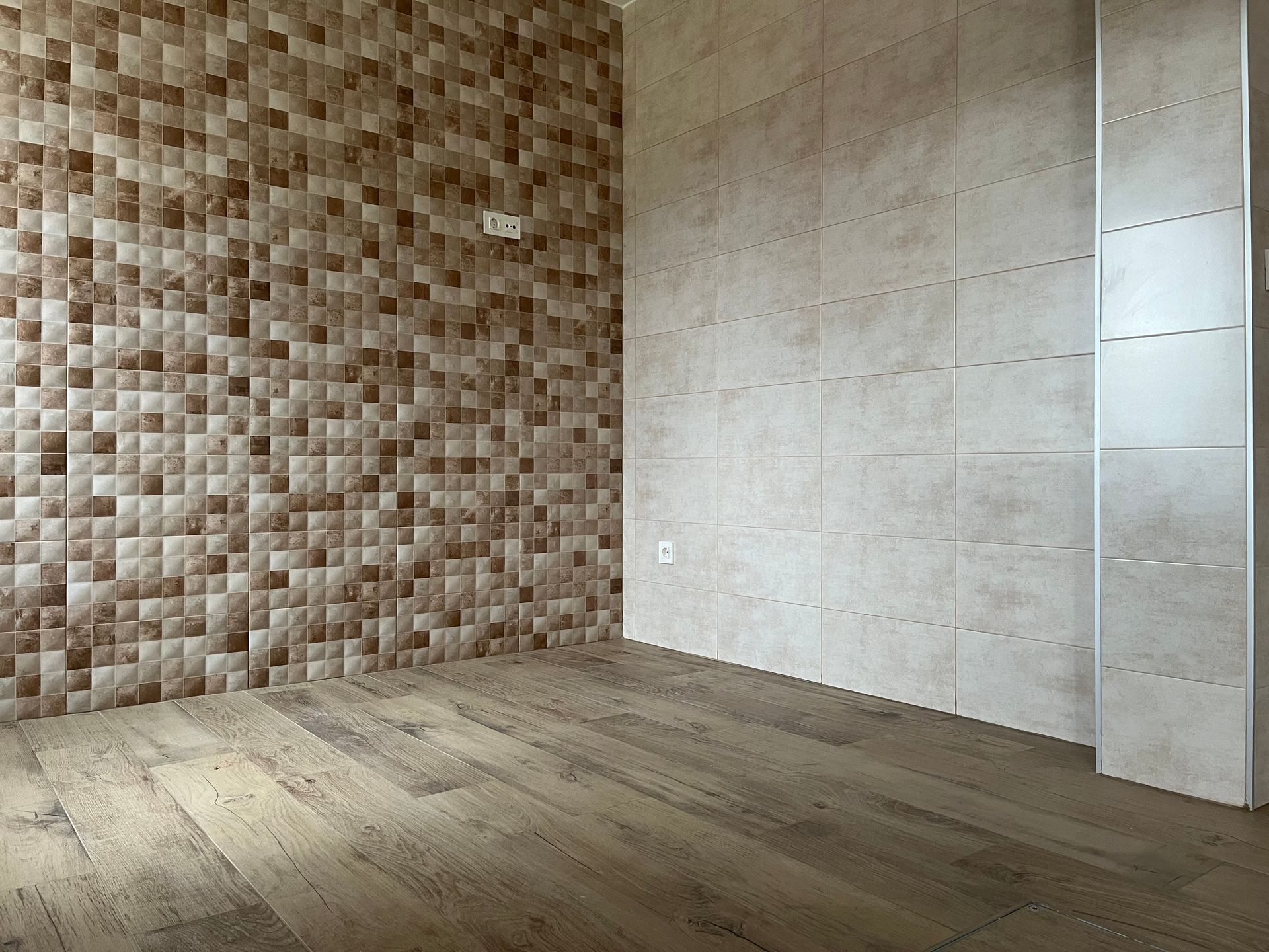Una habitación vacía con una pared de azulejos y suelo de madera.