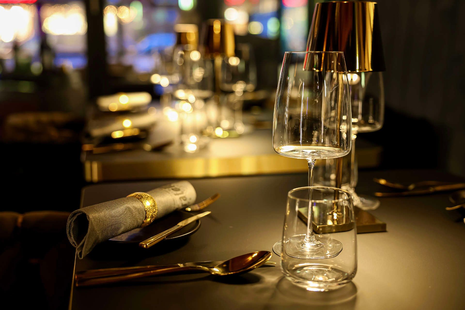 ein Tisch mit Gläsern , Löffeln , Tellern und einer Lampe .