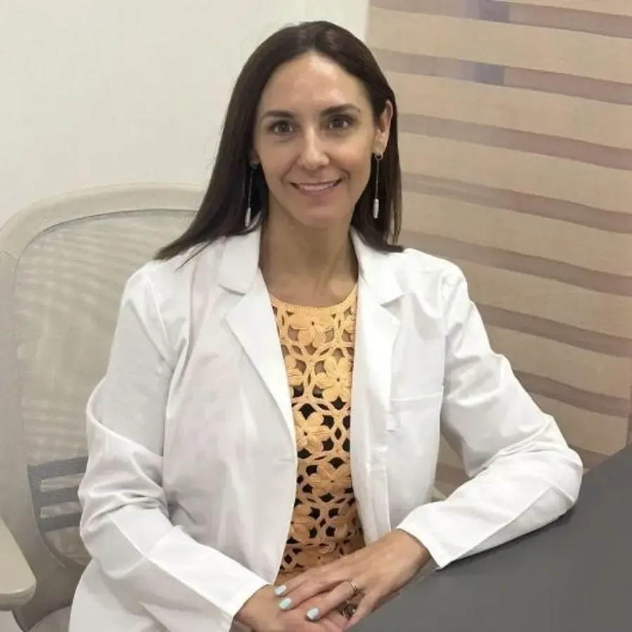 Mujer recibe inyección cosmética en el mentón, ojos cerrados, manos con guantes sosteniendo la jeringa.