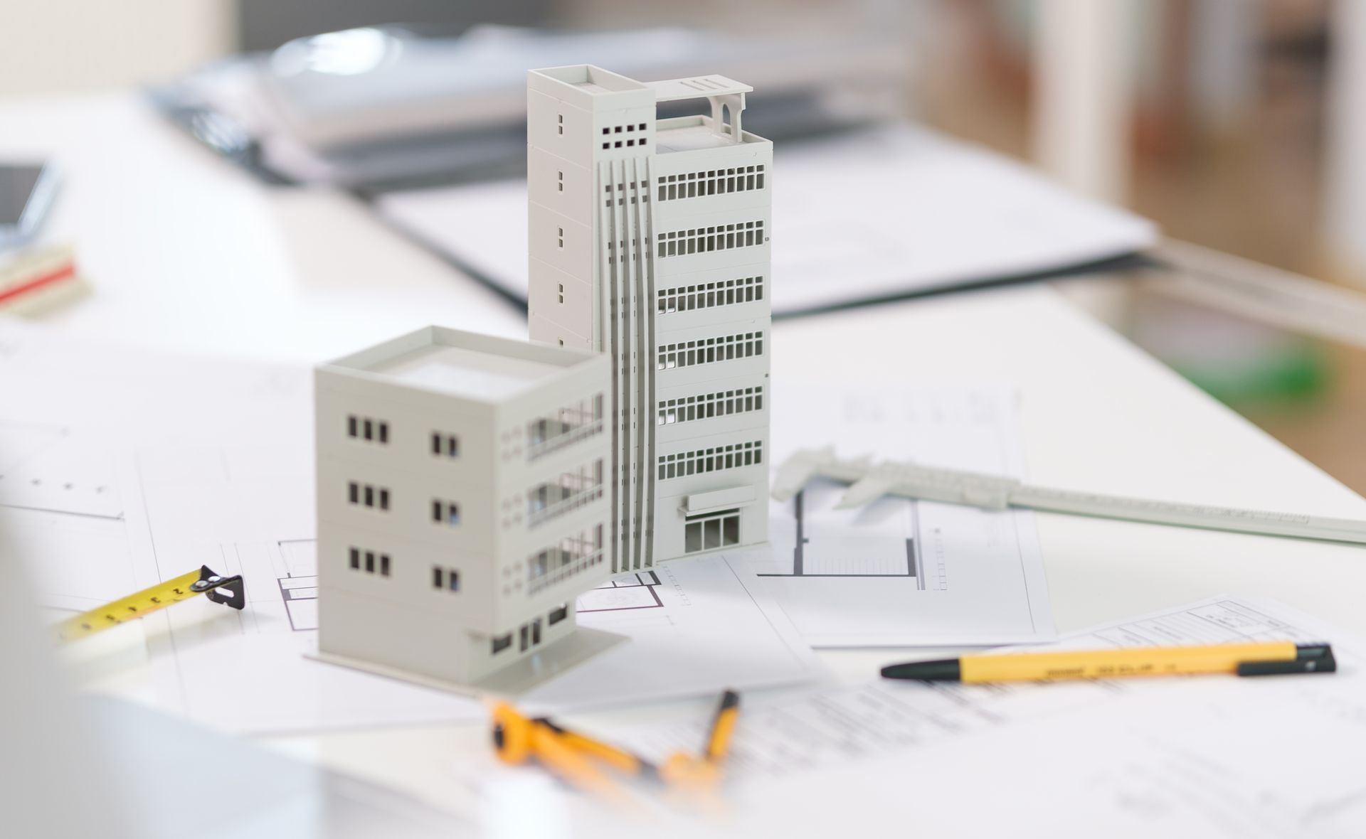 Deux maquettes d'immeubles posées sur des plans de construction