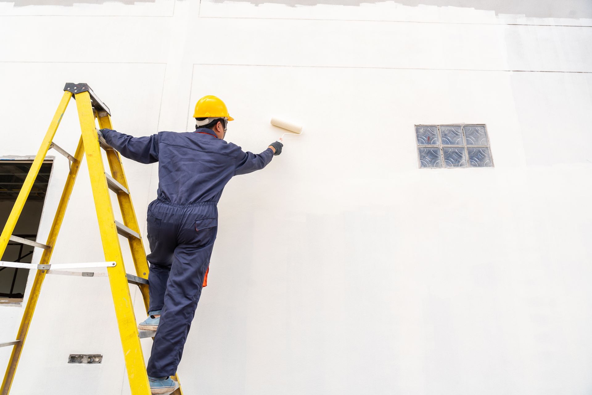 Artisan peignant un mur sur un escabeau