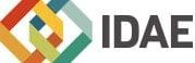Logotipo de IDAE con formas geométricas multicolores entrelazadas y texto gris sobre fondo blanco.