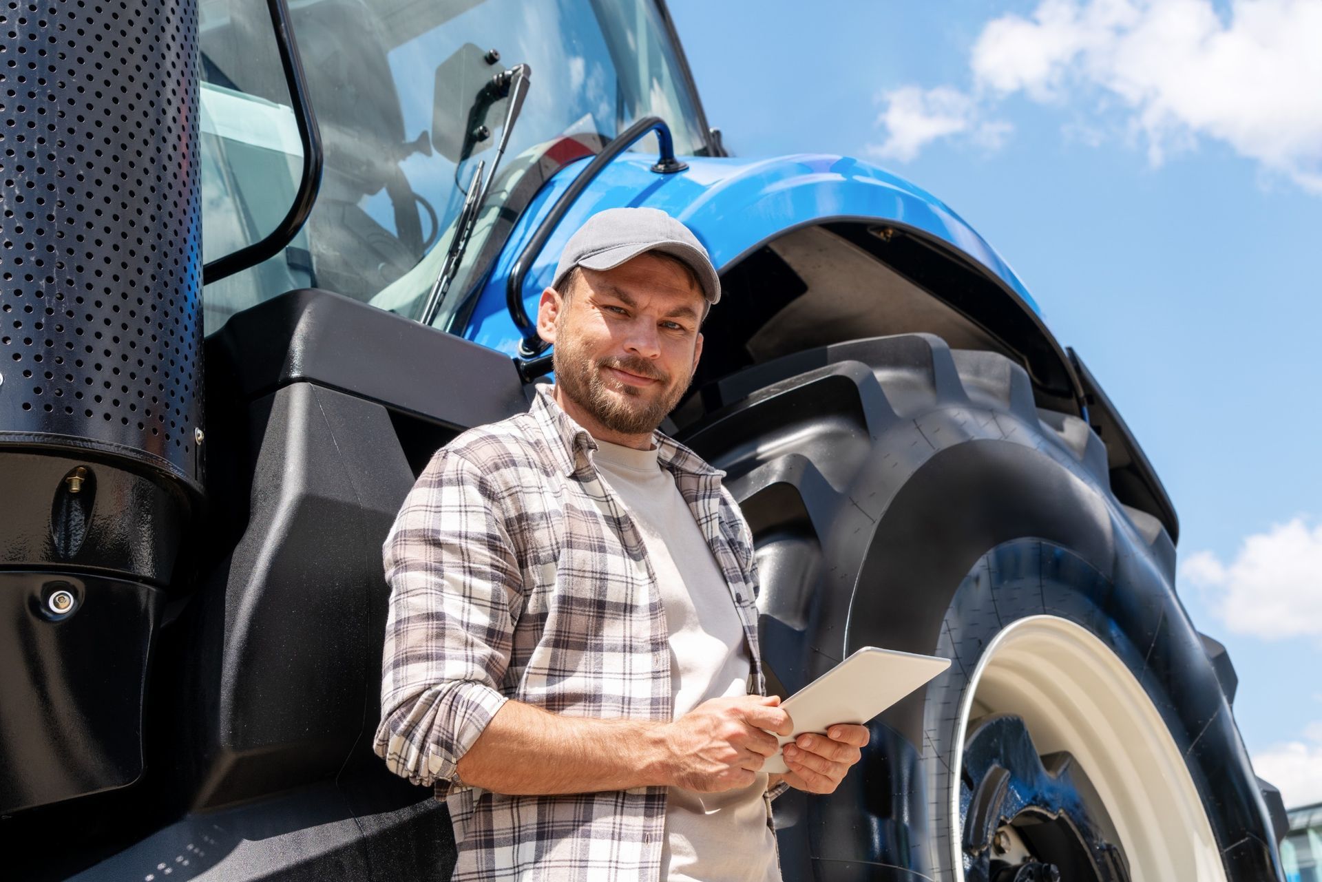 Un hombre está parado frente a un tractor sosteniendo un trozo de papel.