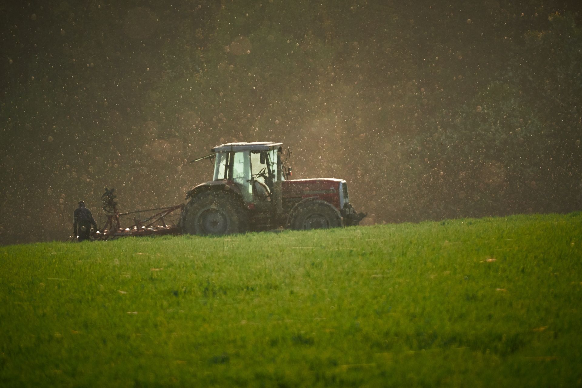 Un tractor está arando un campo bajo la lluvia.