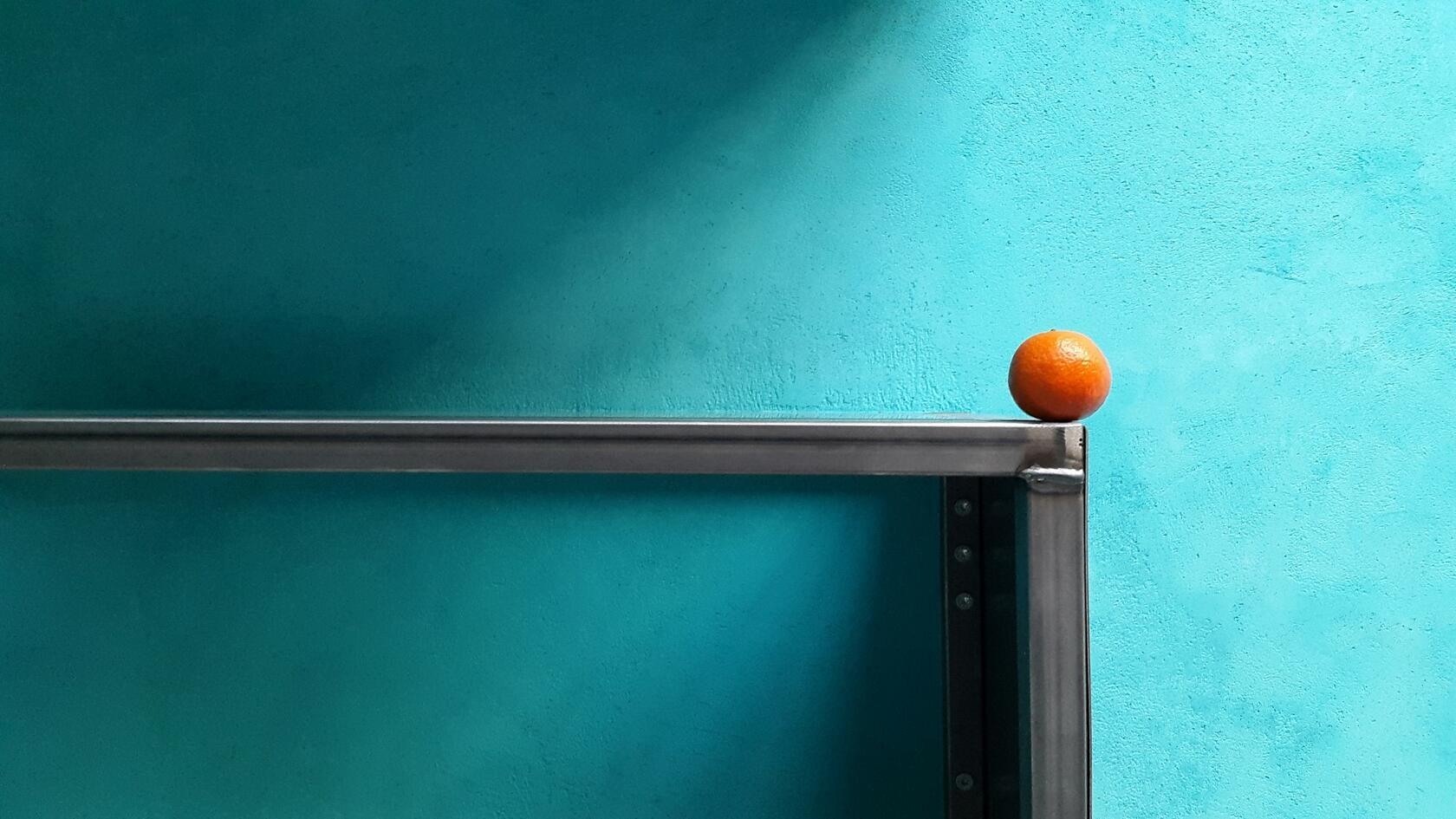 Chaux bleue au mur, orange posée sur une table en premier plan.