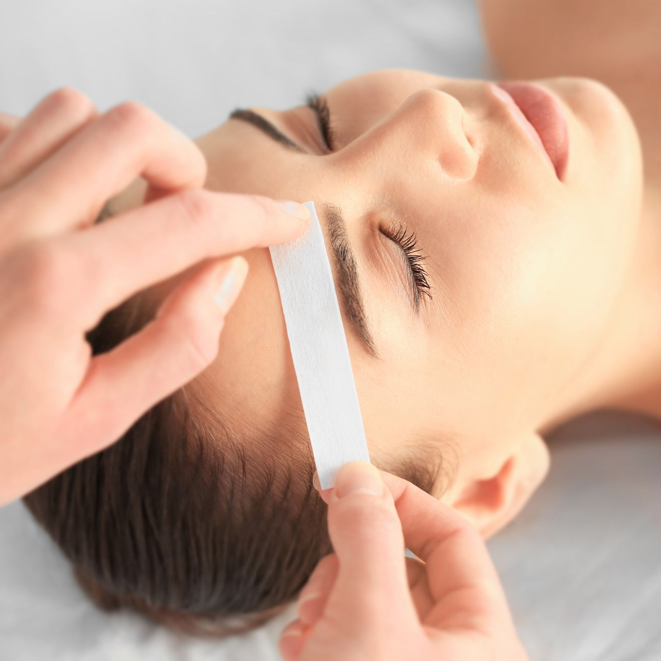 Femme en train de se faire épiler les sourcils avec une bande