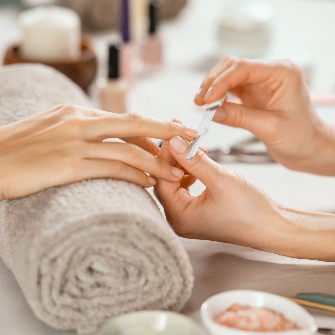 Esthéticienne en train de limer les ongles d'une cliente