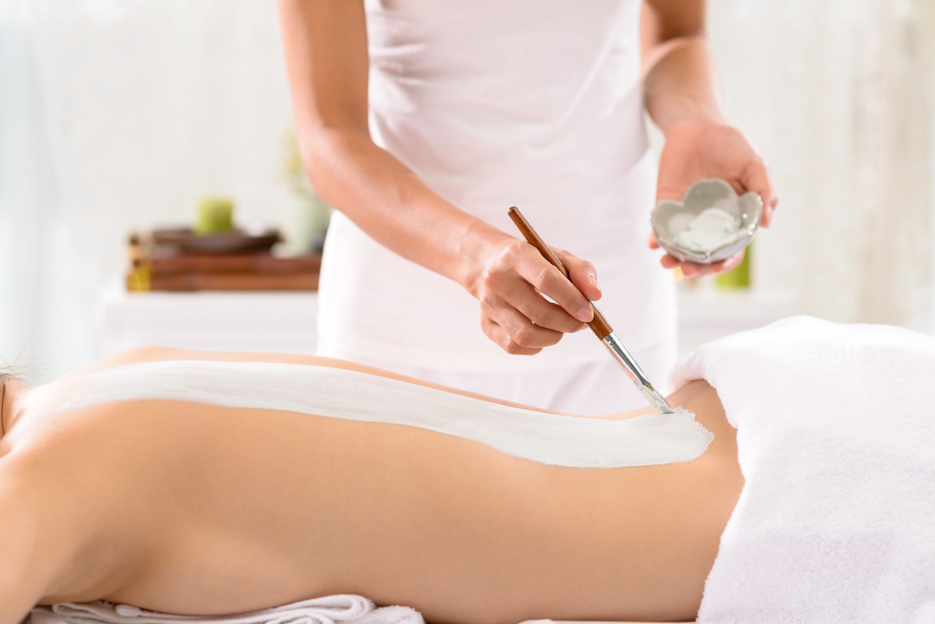 Personne en train d'appliquer un masque blanc dans le dos d'une femme