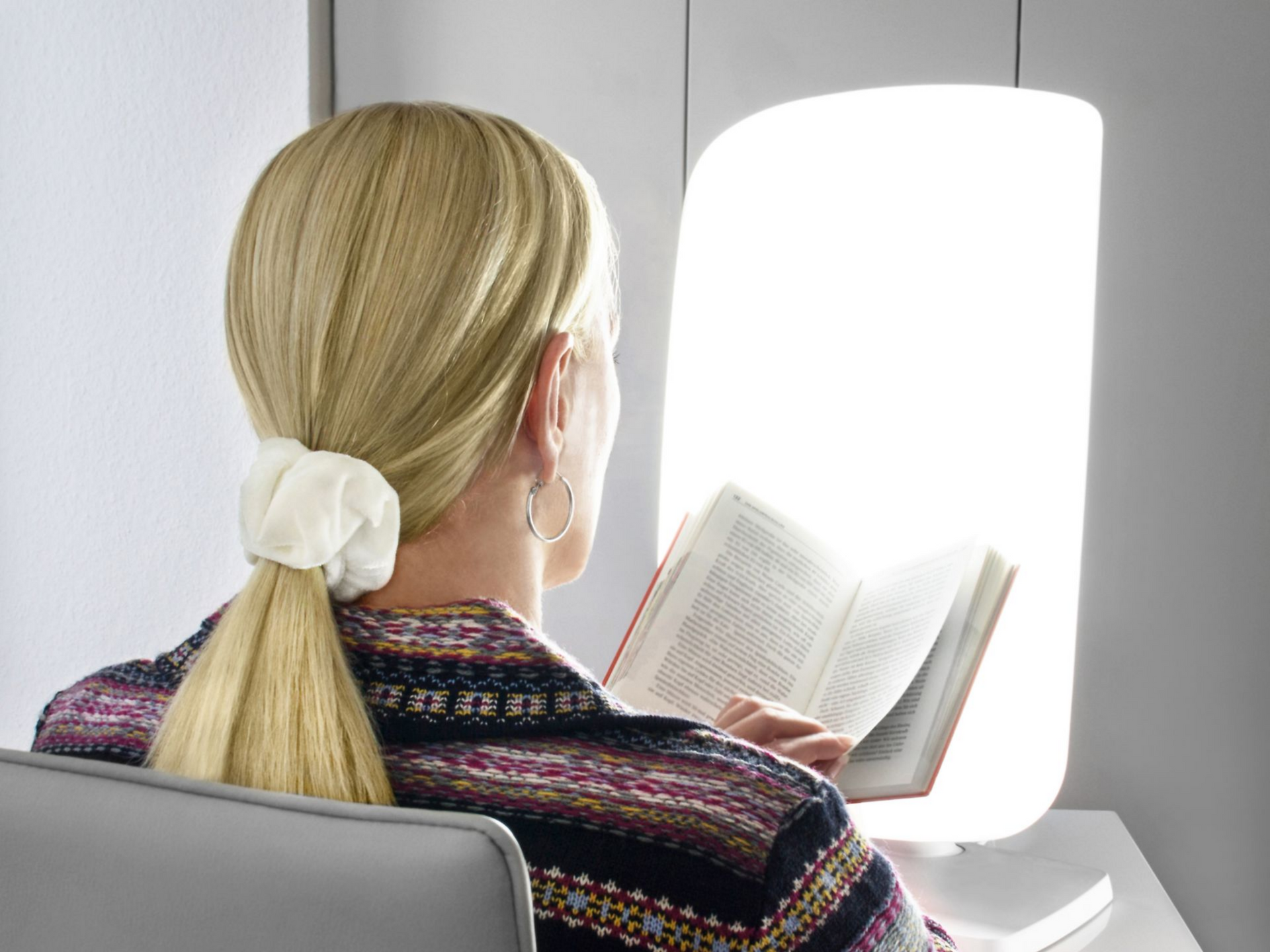 Personne en train de lire un livre devant une lampe de luminothérapie