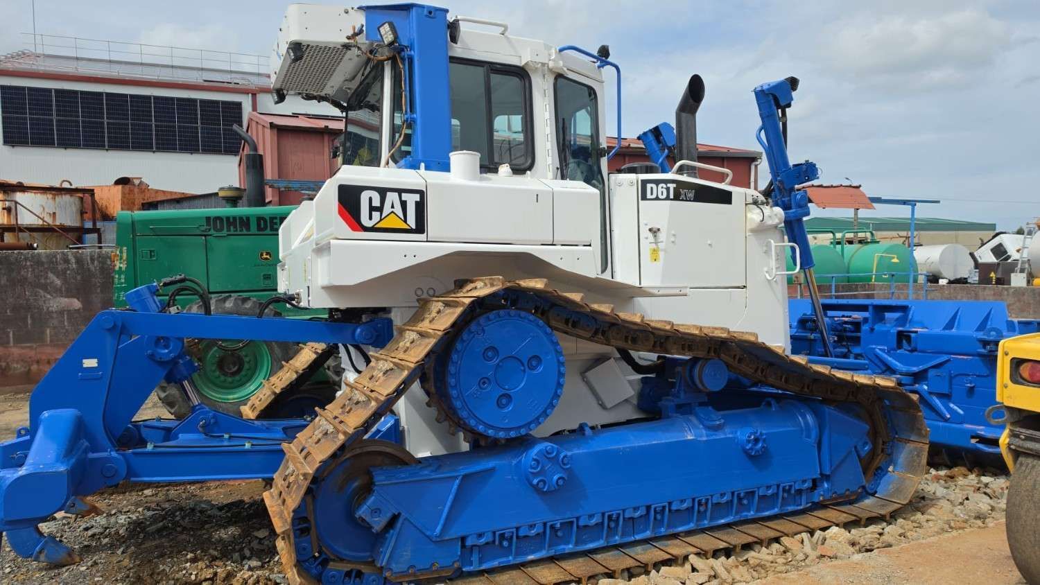 Bulldozer CAT azul con orugas anchas estacionado en terreno fangoso en una obra.
