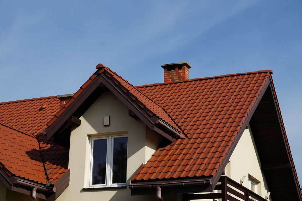 Toit de maison en tuiles rouges avec lucarne.