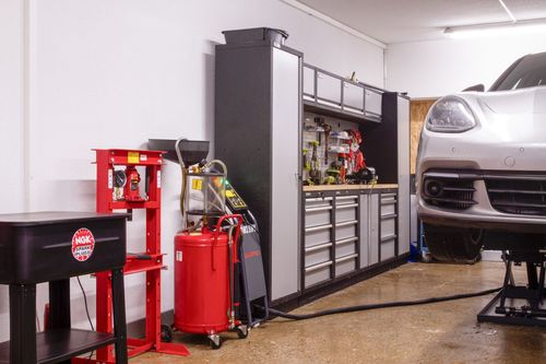 Voitures sur des ponts élévateurs dans un atelier de réparation automobile ; outils et équipements visibles.