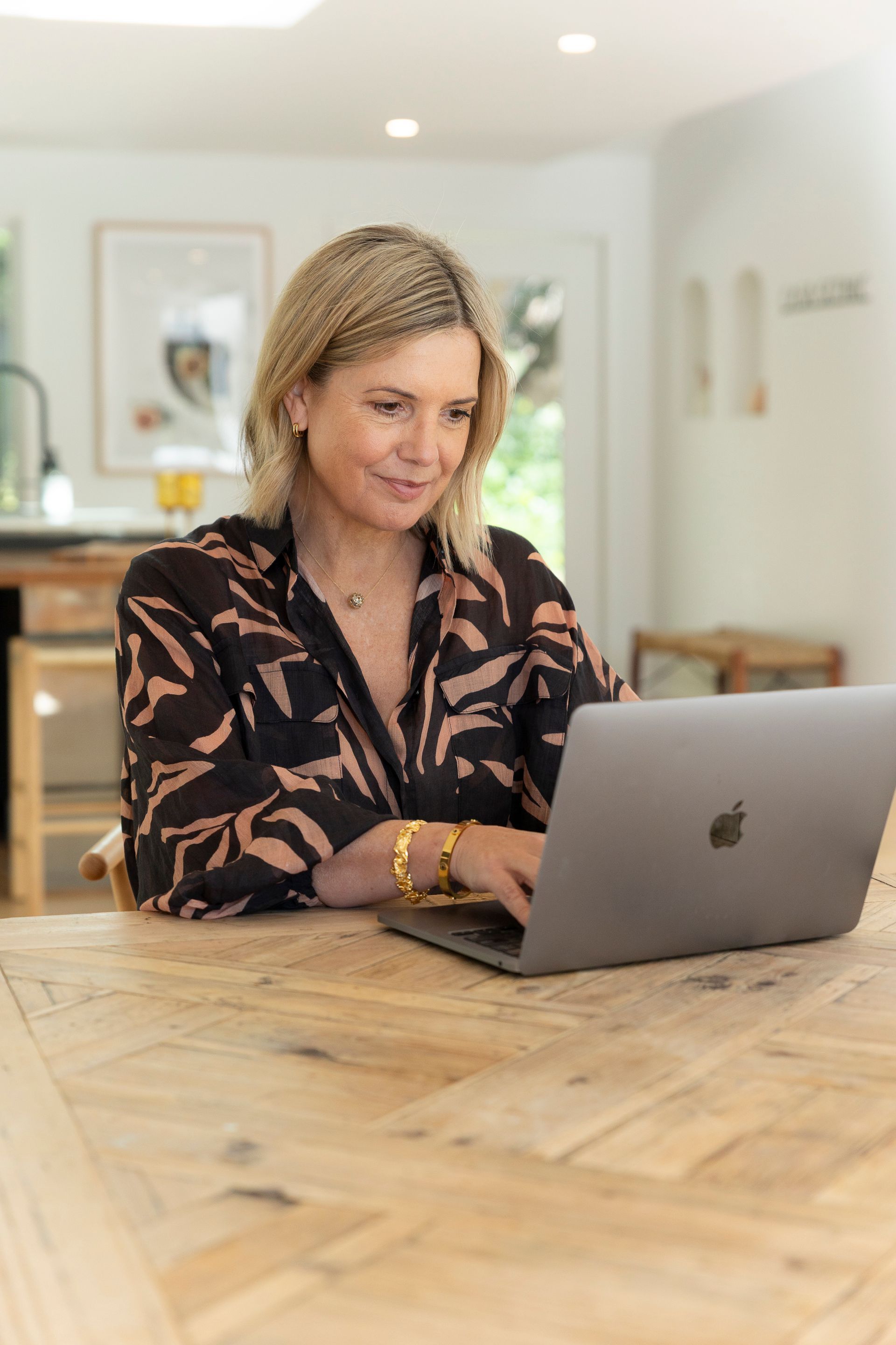 A woman is sitting at a table using a laptop computer.
