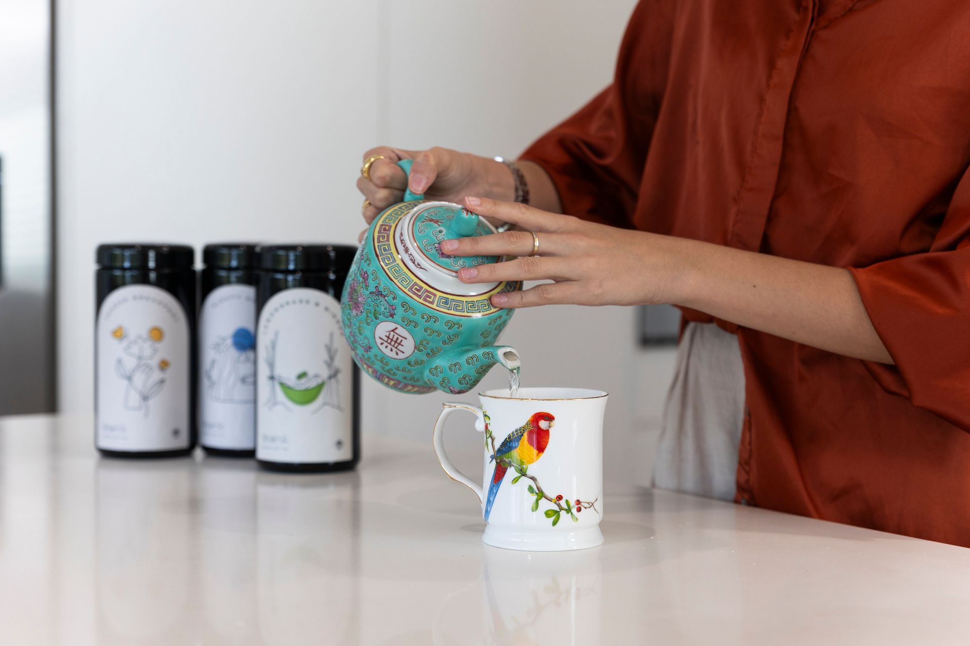 A woman is pouring tea into a mug on a counter.
