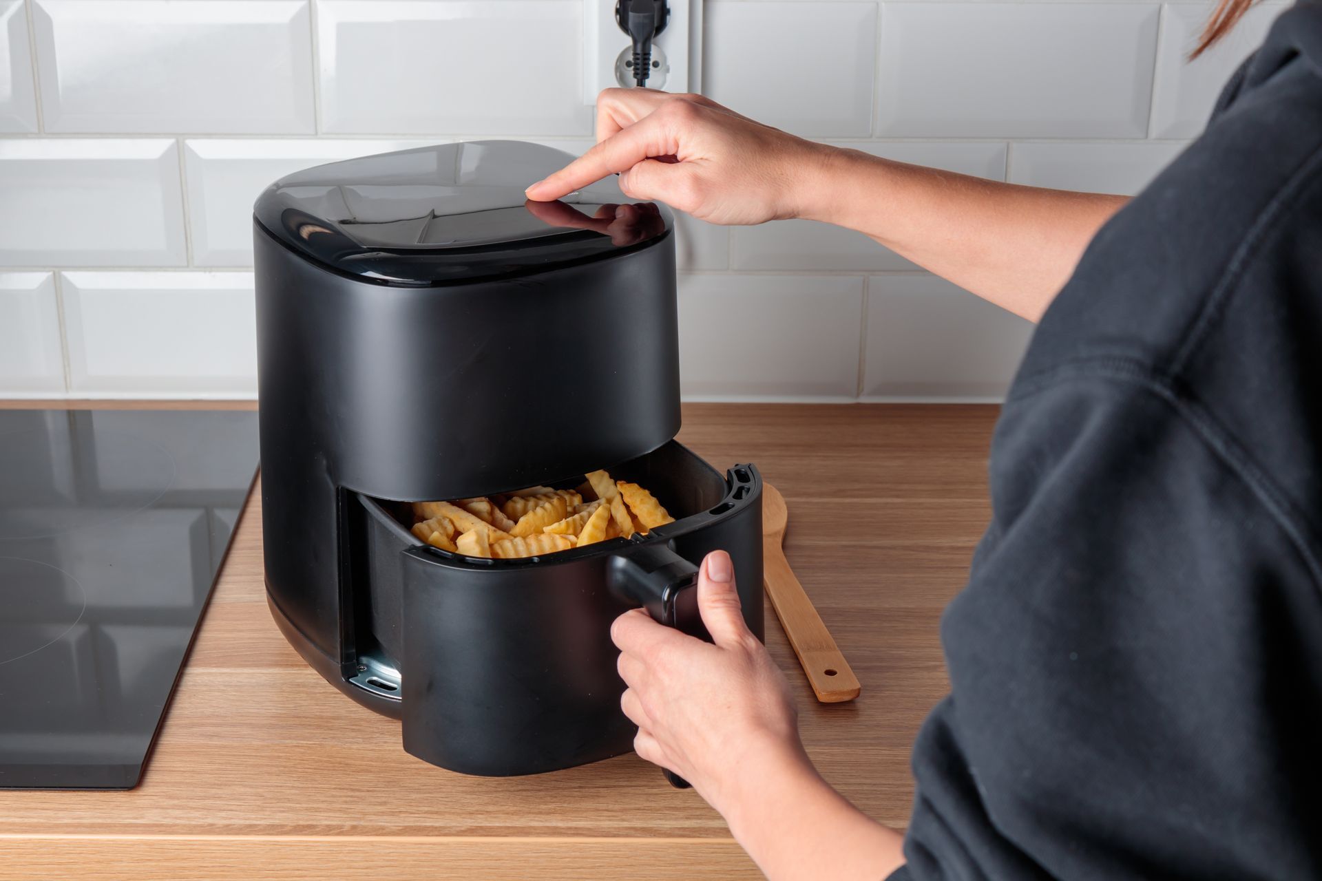 Deux ouvriers installent des meubles de cuisine dans une cuisine lumineuse, l'un sur une échelle et l'autre accroupi avec des outils.