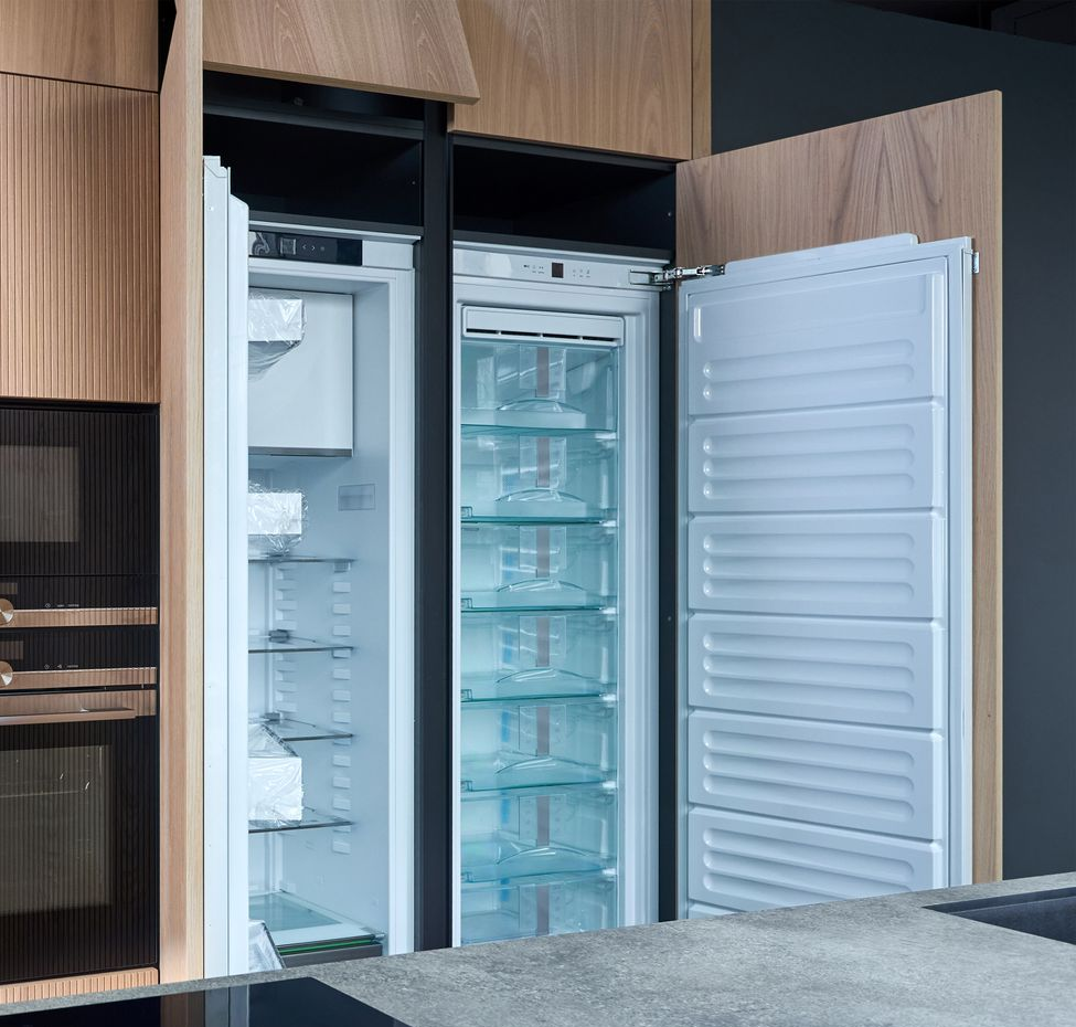 Deux ouvriers installent des meubles de cuisine dans une cuisine lumineuse, l'un sur une échelle et l'autre accroupi avec des outils.