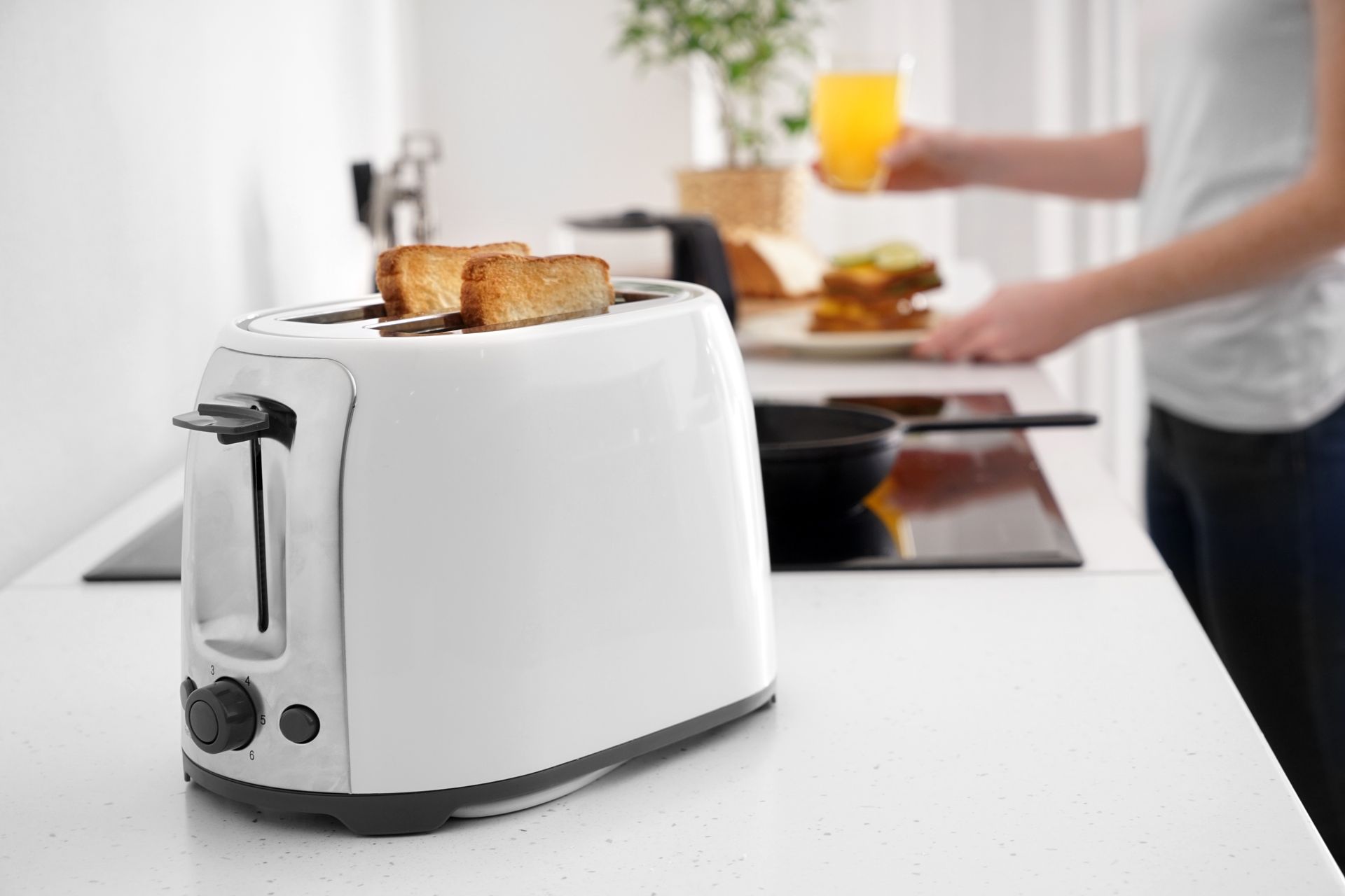 Deux ouvriers installent des meubles de cuisine dans une cuisine lumineuse, l'un sur une échelle et l'autre accroupi avec des outils.