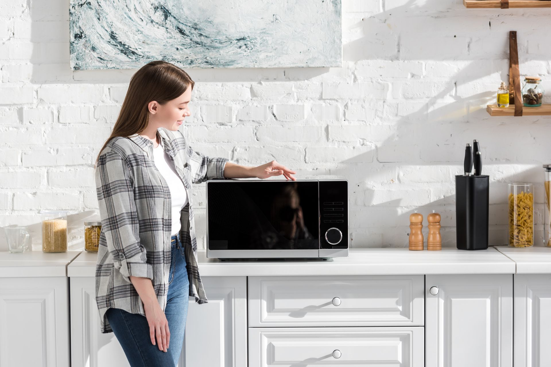 Deux ouvriers installent des meubles de cuisine dans une cuisine lumineuse, l'un sur une échelle et l'autre accroupi avec des outils.