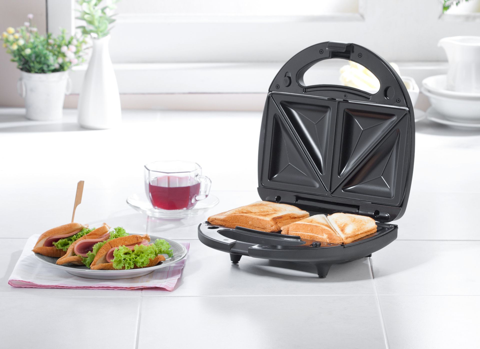 Deux ouvriers installent des meubles de cuisine dans une cuisine lumineuse, l'un sur une échelle et l'autre accroupi avec des outils.