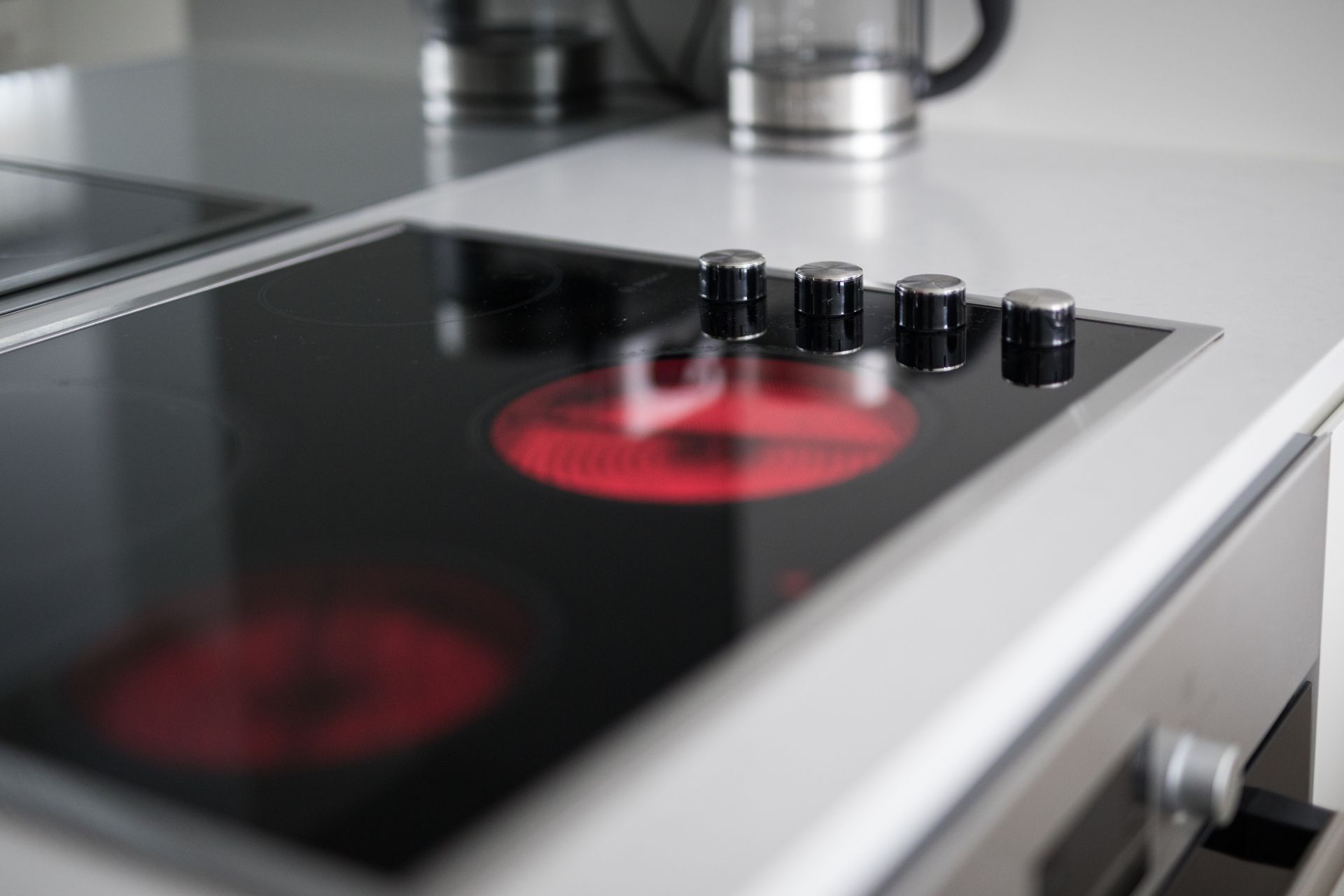 Deux ouvriers installent des meubles de cuisine dans une cuisine lumineuse, l'un sur une échelle et l'autre accroupi avec des outils.
