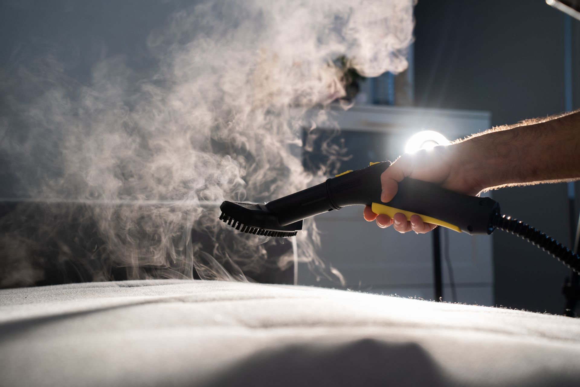 Nettoyage à la vapeur de l'intérieur d'une voiture à l'aide d'une buse manuelle, en pulvérisant une brume sur le siège.